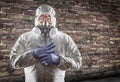 Chinese Man Wearing Hazmat Suit, Goggles and Gas Mask with Brick Wall Background