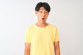 Chinese man wearing yellow casual t-shirt standing over isolated white background afraid and shocked with surprise expression, Royalty Free Stock Photo