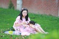 A Chinese mother feed little baby girl on the lawn Royalty Free Stock Photo