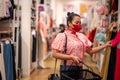 Chinese New Year, asian woman wearing mask to protect against corona virus and shopping and choosing fashionable clothes indoor at Royalty Free Stock Photo