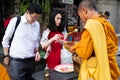 Thai couple making an offering to a Thai monk in the early morning in Bangkok