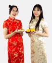 Chinese new year concept. Two Asian women in Cheongsam dres holding plate of tea and oranges