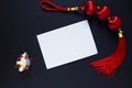 Chinese New Year dcer and blank paper card on black. Oriental lucky knot and maneki neko cat figurine. Royalty Free Stock Photo