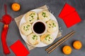 Chinese New Year decoration with dumplings, tangerines, soy sauce, chopsticks, red envelopes on gray concrete background. Happy Royalty Free Stock Photo
