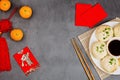 Chinese New Year decoration with dumplings, tangerines, soy sauce, chopsticks, red envelopes on gray concrete background. Happy Royalty Free Stock Photo