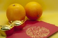 Chinese New Year decoration with oranges, red packets and gold ingots on yellow cover background.