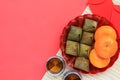 Sweet stuffed dough pyramid, orange, tea and red envelope on white bamboo mat. Royalty Free Stock Photo