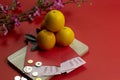 Chinese new year fresh oranges and angpao pocket with wooden board and cherry blossom flower on red paper background Royalty Free Stock Photo