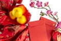 Chinese new year fresh oranges and Angpao pockets on red Chinese fabric and cherry blossom branch border on white background Royalty Free Stock Photo