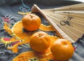 Chinese New year, tangerines and a fan lying on the silk fabric with an embroidered dragon