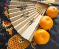 Chinese New year, tangerines and a fan lying on the silk fabric with an embroidered dragon