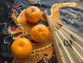 Chinese New year, tangerines and a fan lying on the silk fabric with an embroidered dragon