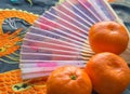 Chinese new year-traditional pink fan and tangerines on silk fabric, background with embroidered dragon Royalty Free Stock Photo