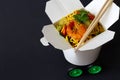 Chinese noodles with shrimps and vegetables in take-out box with car wheels. Creative chinese food delivery concept