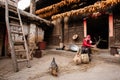 Chinese old man making a corn chair in front of old charming Chinese house, beautiful art wooden texture, corn drying hanging over