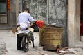 Chinese old man trash keeper find and pickup recyclable waste in garbage bin to basket of bicycle in small alley at China