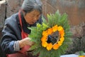 Chinese old woman wreathed flowers into a garland.