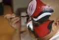 A chinese opera actor is painting his face