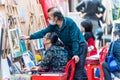 A Chinese painter teacher teaching his student painting on canvas during the Covid pandemic in the Dafen Oil painting village,