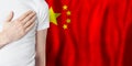 Chinese person with hand on heart on the background of China flag. Patriotism, country, national, pride concept