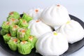 Varitirs steamed stuff bun and green chinese steamed dumpling with pork served in black disk Royalty Free Stock Photo