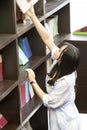 Chinese Portrait of young beautiful woman reaching for a library book In Bookstore