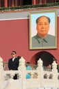 Chinese security officer on the background of a portrait of Mao Zedong