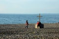 Chinese Singapore tourists at Christian cross crucifix on rocky Black Sea beach seafront Batumi Georgia