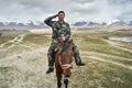 Chinese soldier riding a horse near Karakul Lake salutes to camera, China