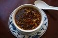 Chinese soup spicy and sour in a bowl with porcelain spoon on a brown table, selected focus Royalty Free Stock Photo