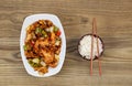 Chinese Spicy Chicken Dish with Rice in bowl on faded wood