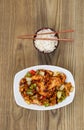 Chinese Spicy Chicken Dish with Rice in bowl on faded wood