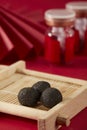 Chinese style red background with red folding fan and red pill bottle, three Chinese medicine pills placed on bamboo basket