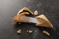 Chinese fortune cookies, one is cracked with blank paper slip for the prediction on a dark slate background with copy space Royalty Free Stock Photo