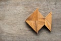 Chinese tangram puzzle in fish shape on wood background