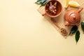 Chinese tea ceremony. Ceramic teapot, teacup, green leaves, wooden spoon with dried tea on bamboo mat on yellow background. Top Royalty Free Stock Photo