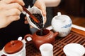 Chinese tea ceremony. Girl pours tea leaf into a teapot.