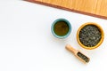 Chinese tea concept. Tea ceremony. Dry tea leaves in bowl and wooden scoop near cup of tea on white background and Royalty Free Stock Photo