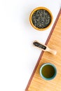 Chinese tea concept. Tea ceremony. Dry tea leaves in bowl and wooden scoop near cup of tea on white background and Royalty Free Stock Photo