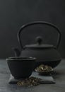 Chinese teapot with plate of loose black tea and cup on black background Royalty Free Stock Photo