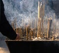 Chinese temple censers are filled with burning incense and surrounded by smoke.