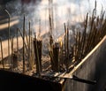 Chinese temple censers are filled with burning incense and surrounded by smoke.