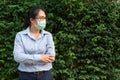 Chinese-Thai asian business woman  on green fence background. Female doctor wear glasses with sterile face mask hands Royalty Free Stock Photo