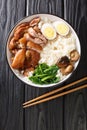 Chinese Thai food Khao Kha Moo Jasmine rice with stewed pork leg boiled eggs, mushrooms closeup in the bowl. Vertical top view Royalty Free Stock Photo