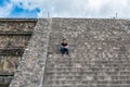 A Chinese tourist sitting on steps in the ruins of the architecturally significant Mesoamerican pyramids and green grassland