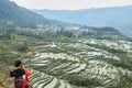 Chinese tourist taking pictures of the YuanYang rice terraces from the top of a cliff. YuanYang rice terraces in Yunnan, China, ar