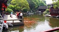 Chinese tourists feeding koi carp in a traditional garden, China