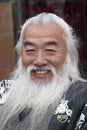 Elderly smiling Chinese man with white hair and traditional beard