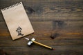 Chinese traditional calligraphy concept. Asian hieroglyph love in craft paper notebook near special writting pen on dark Royalty Free Stock Photo