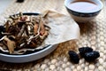 Chinese traditional medicine script. Herbal tea with jujubes, goji berries, gingseng roots and others on parchment paper on neutr